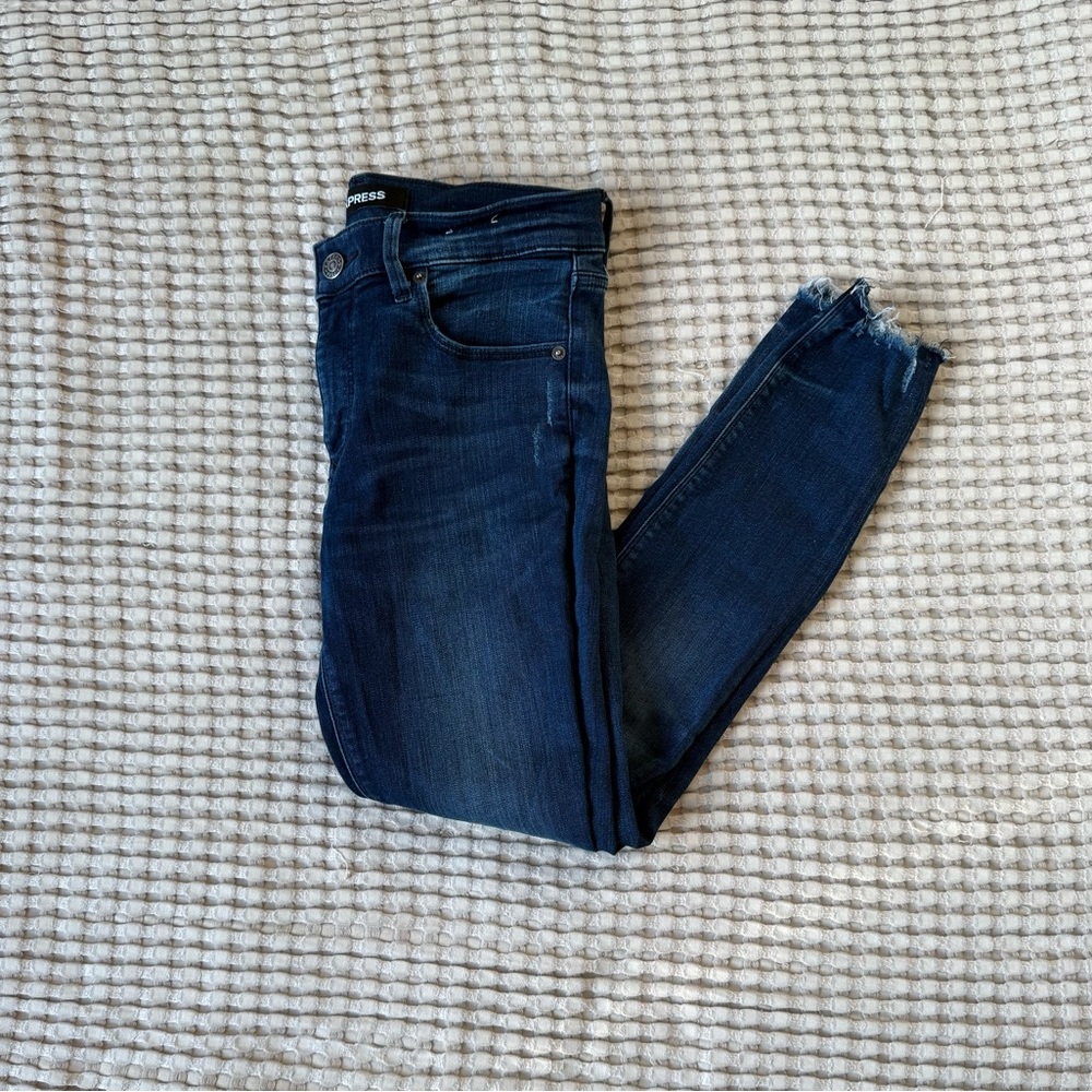 Express dark wash skinny jeans with distressed bottoms.
